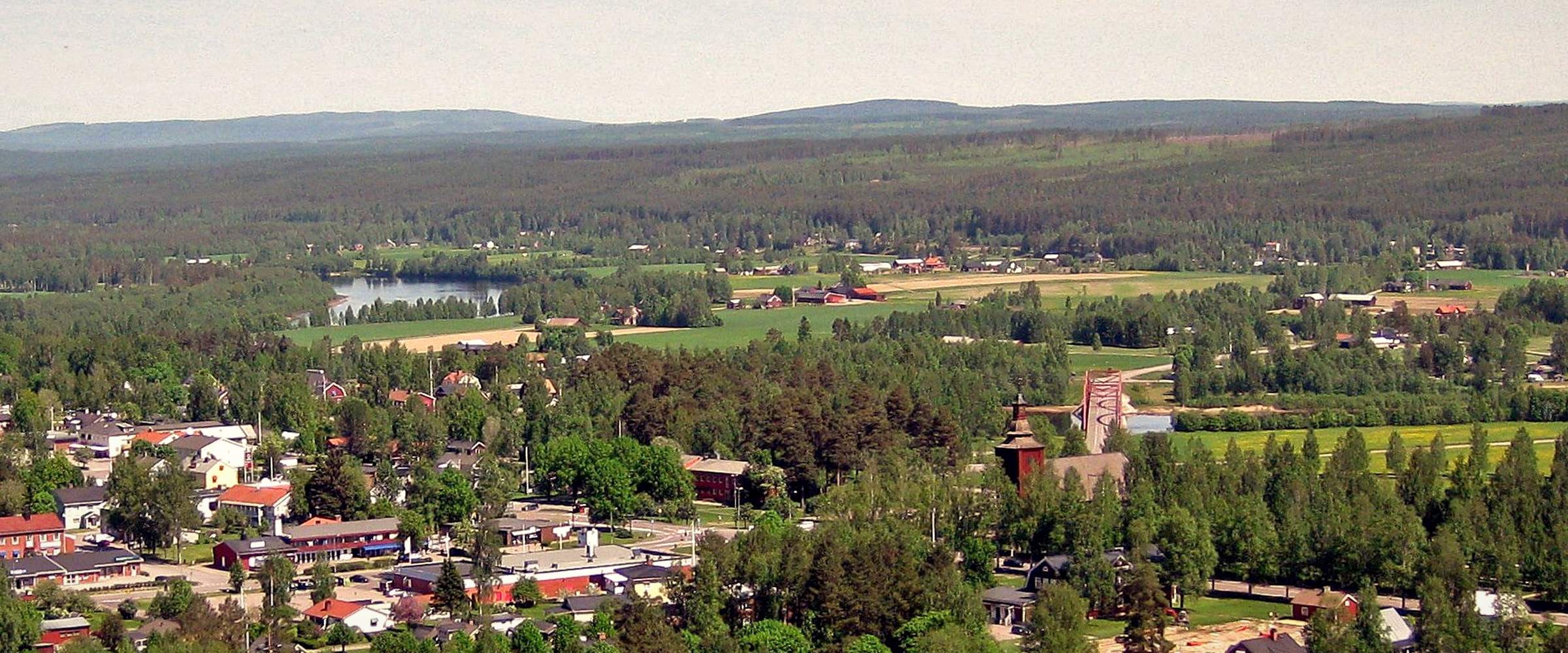 Ekshärad från ovan, med hus bland träden och skogsklädda åsar bakom