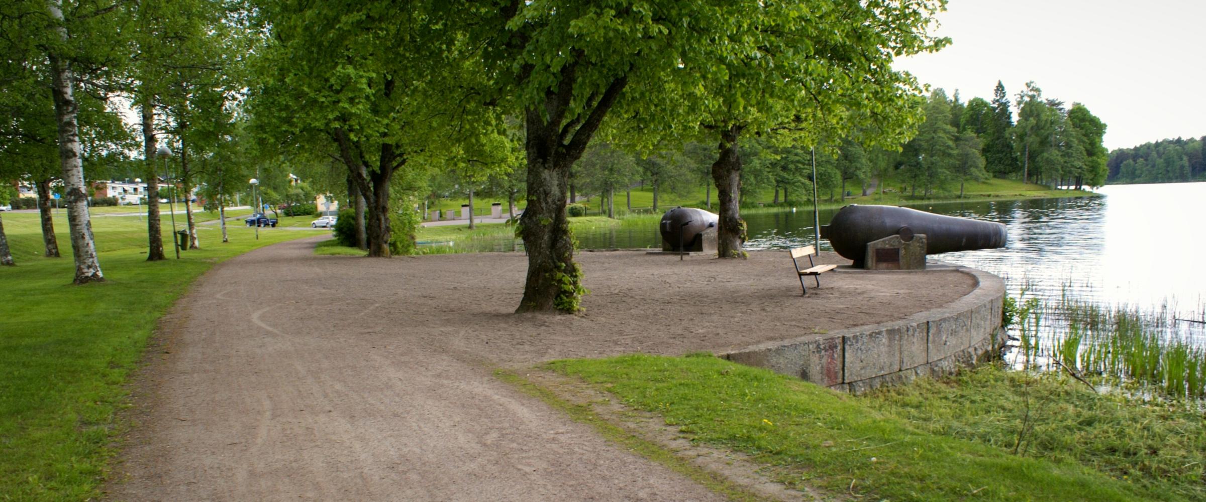 Grusväg genom en park med lövträd vid sjön i Filipstad