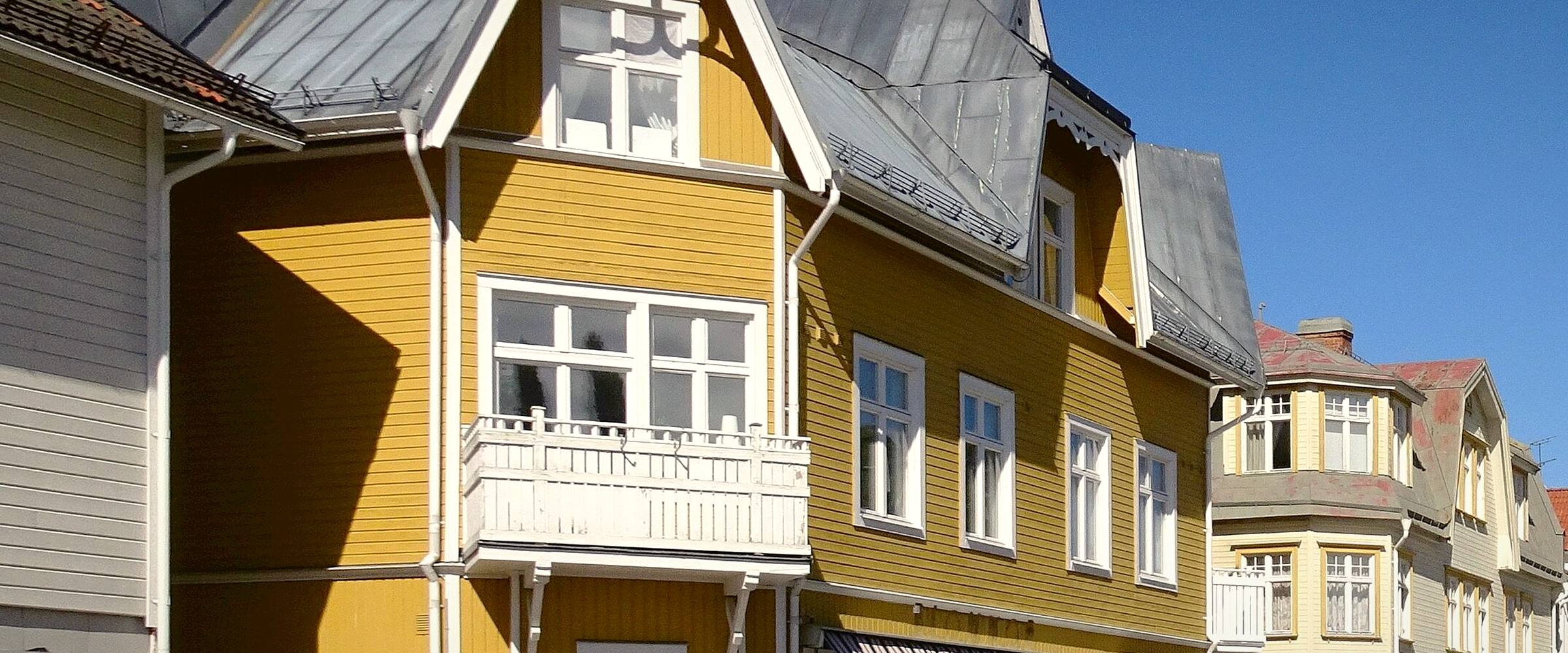 Järnvägsgatan i Vansbro med ett gult trähus med snickarglädje och vita balkonger