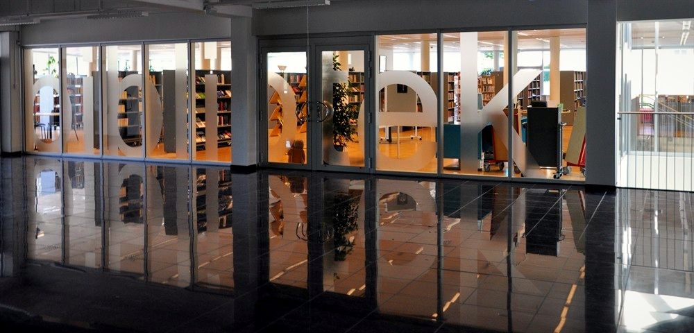 Biblioteket med blankt mörkt golv och glasväggar