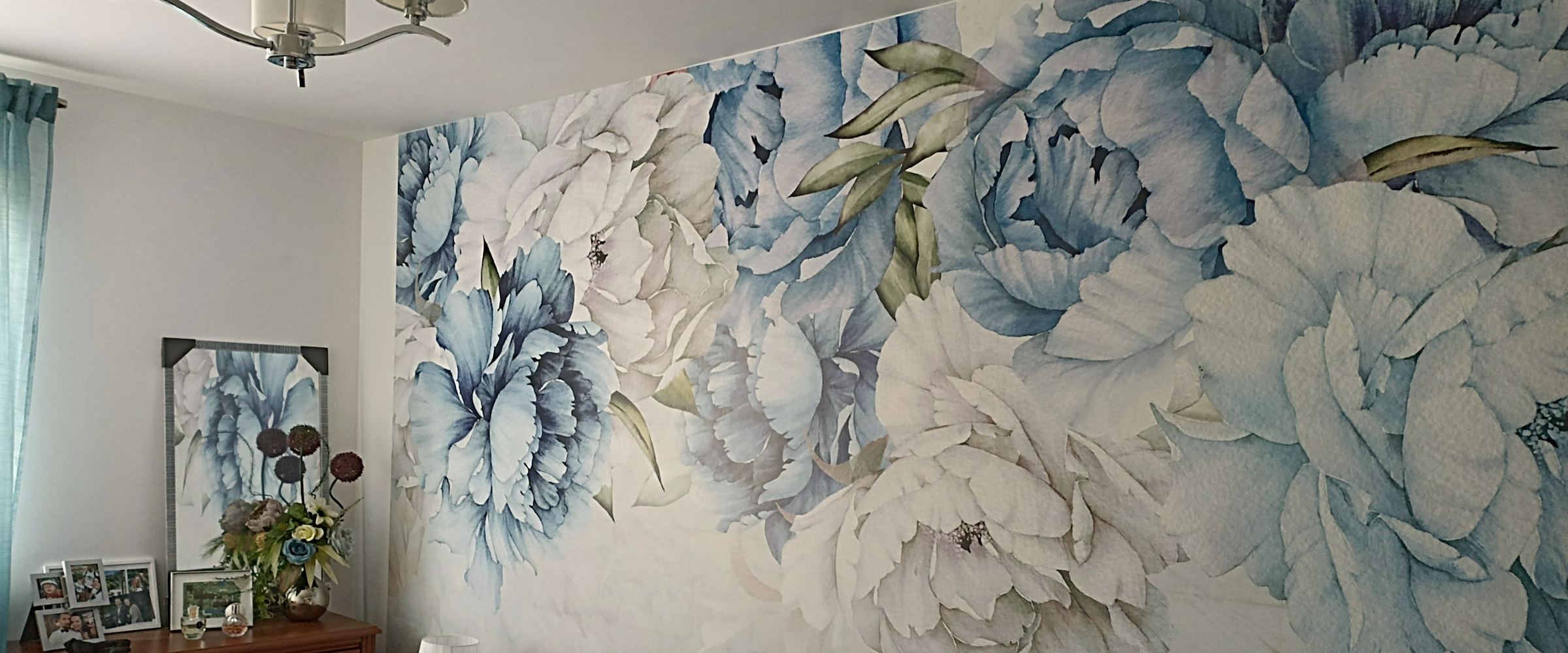 Sovrum med tapet i stora blå blommor bakom sängen